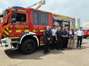 Bild vergr&ouml;&szlig;ern: Vor einem Feuerwehrauto stehen viele Menschen. Das Auto ist neu und wurde der Feuerwehr gerade &uuml;bergeben.